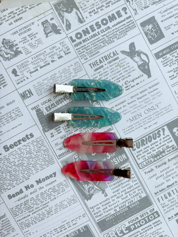 Set of four colorful hair clips on a newspaper background