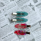 Set of four colorful hair clips on a newspaper background