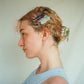 Woman with styled hair featuring decorative hair clips against a plain background