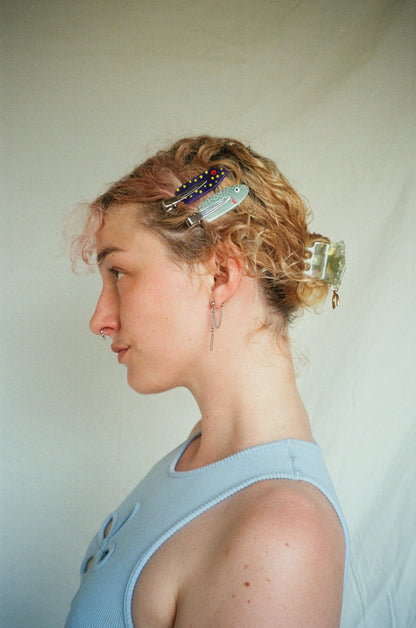 Woman with styled hair featuring decorative hair clips against a plain background
