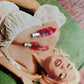 Woman lying on a green couch with red and gold hair clips in her hair, surrounded by text.