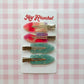 Set of colorful hair clips on a card with 'Hey Ricochet' branding against a pink checkered background.
